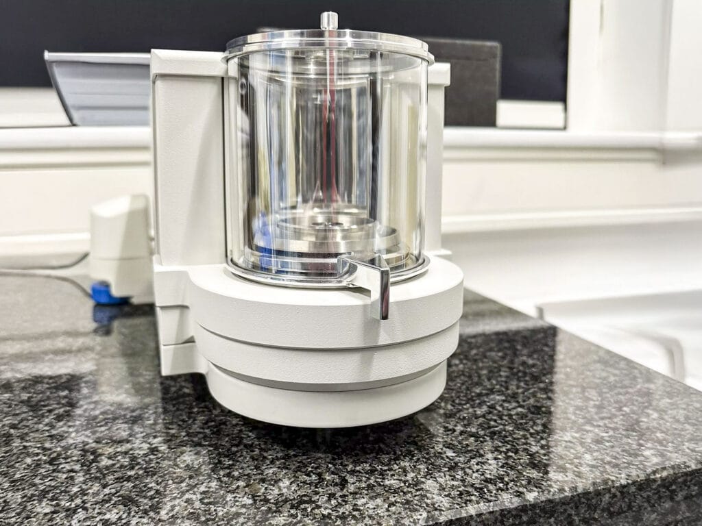 Weiße Ultra-Mikrowaage RADWAG ELLIPSIS UYA-6.5Y auf dunkler Granitoberfläche im Max-Born-Institut. Transparente Messkammer, moderner Look, helle Umgebung.