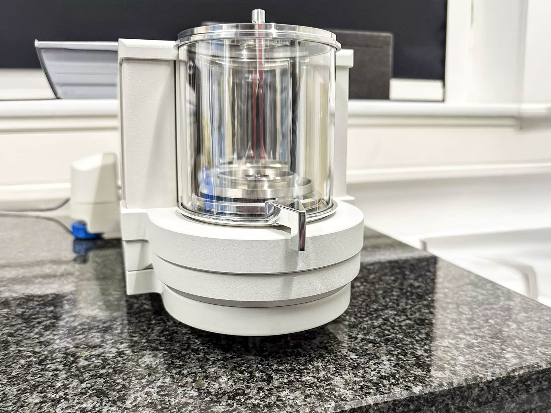 Weiße Ultra-Mikrowaage RADWAG ELLIPSIS UYA-6.5Y auf dunkler Granitoberfläche im Max-Born-Institut. Transparente Messkammer, moderner Look, helle Umgebung.