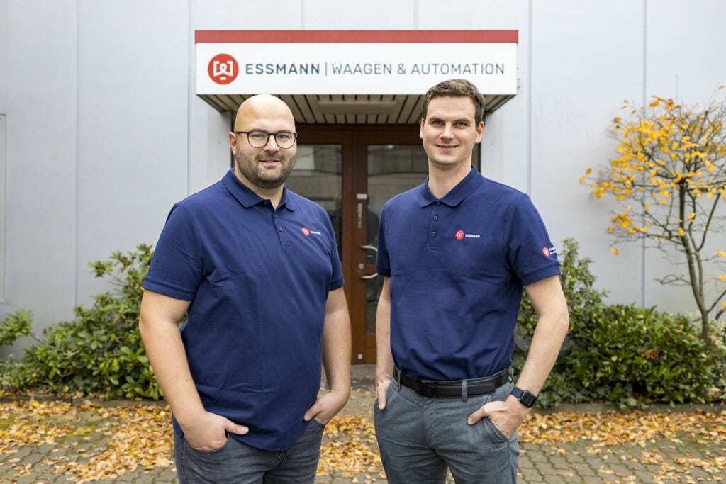 Die beiden neuen Kollegen Dominik Vollbrecht und Markus Wehebrink vor der ESSMANN-Firmenzentrale in Hamburg. Im Hintergrund sieht man das Schild ESSMANN | Waagen & Automation