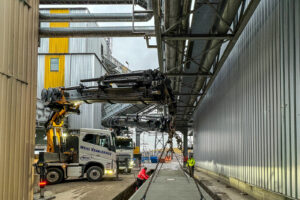 Kran hebt Wägebrücke aus Beton in der AVIRETTA Industrieanlage unter einer Rohrbrücke auf das Fundament