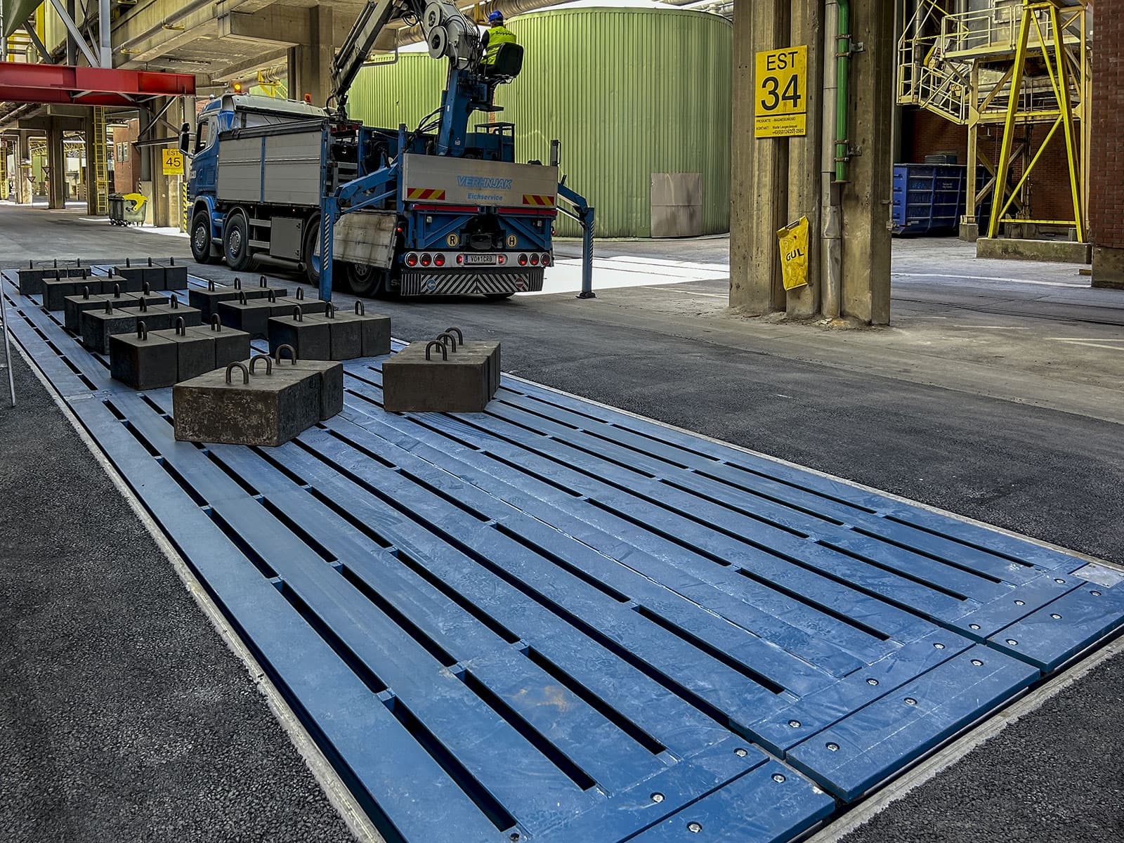 Industriegebiet mit Kran und Prüfgewichten auf Unterflurwaage zur Eichung