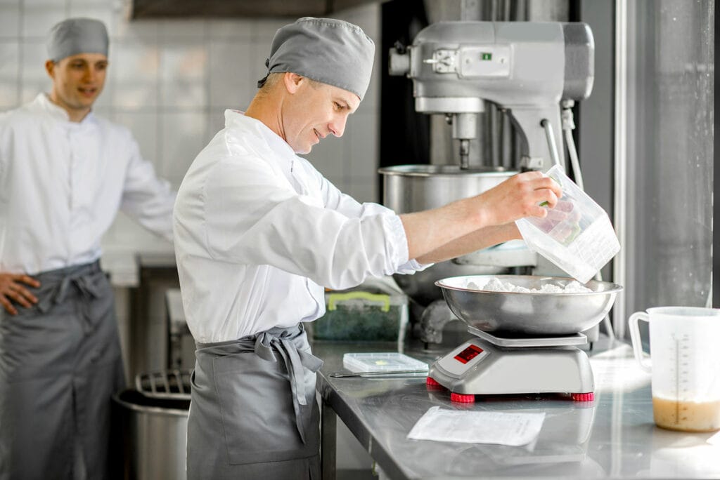 Bäcker wiegt Zutaten in Backstube auf einer OHAUS-Waage ab
