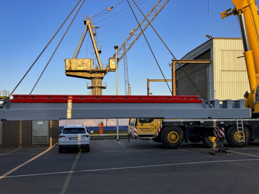 Crane lifts rail scales with red rails into position