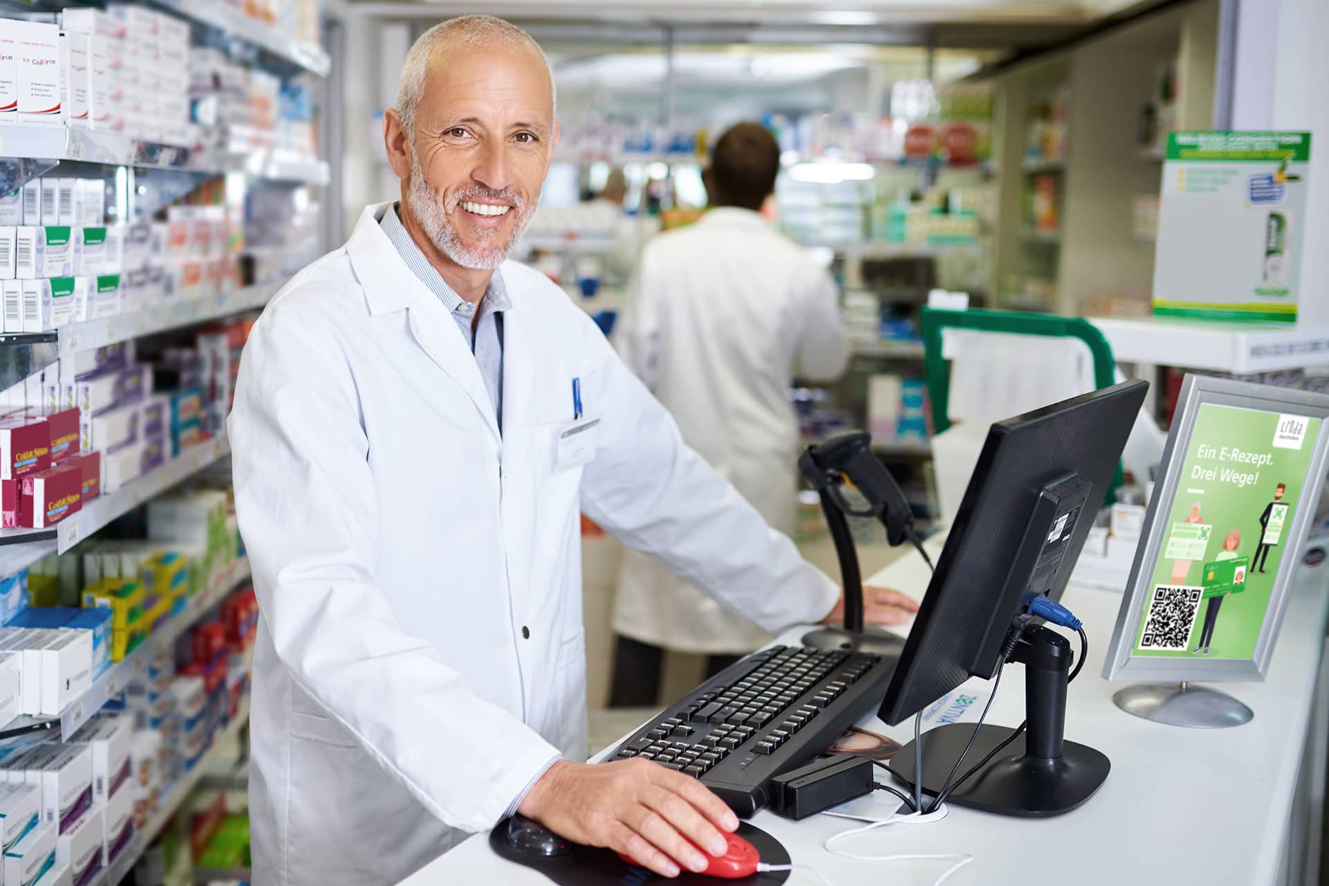 Apotheker lächelt hinter Theke in Apotheke