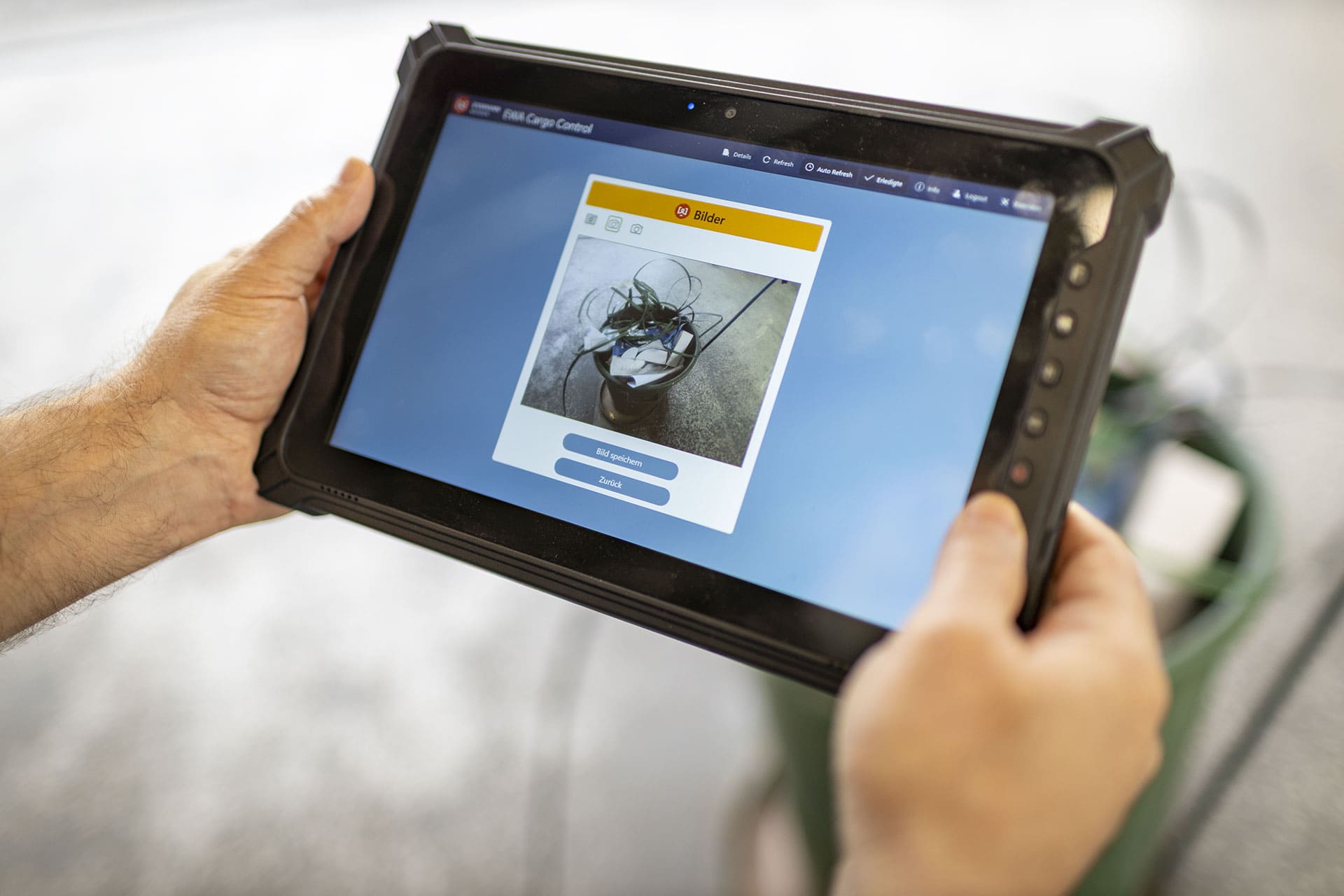 Person fotografiert Inhalt eines Abfallbehälters auf einem Rugged Tablet