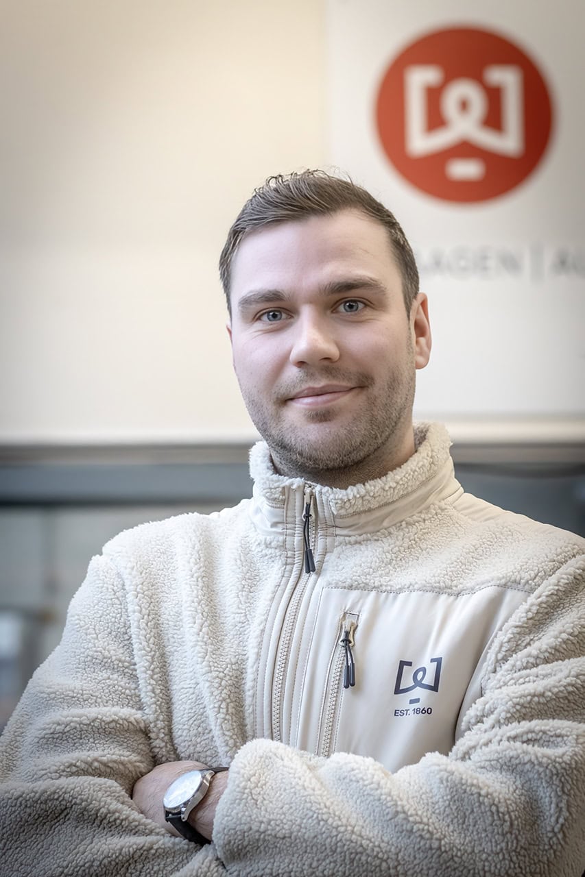 Mann im beigen Fleece vor Firmenlogo