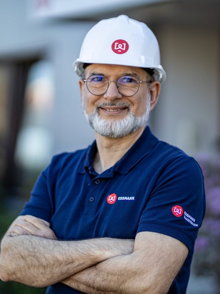 EWP-Entwickler Sharam Gödel mit weißem Schutzhelm und verschränkten Armen vor dem ESSMANN-Gebäude in Hamburg