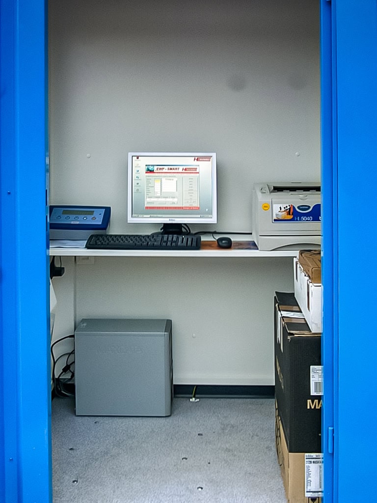 Kleiner Computerarbeitsplatz hinter blauen Türen in einem Container
