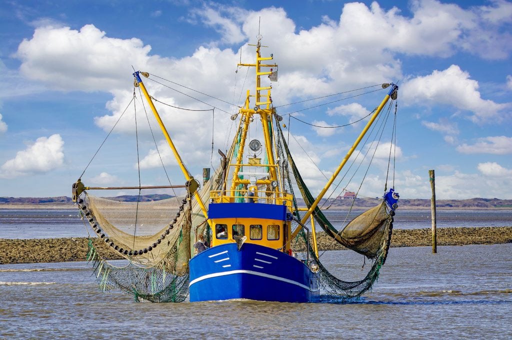 Een blauw-gele krabvisser met uitgespreide visnetten op zee