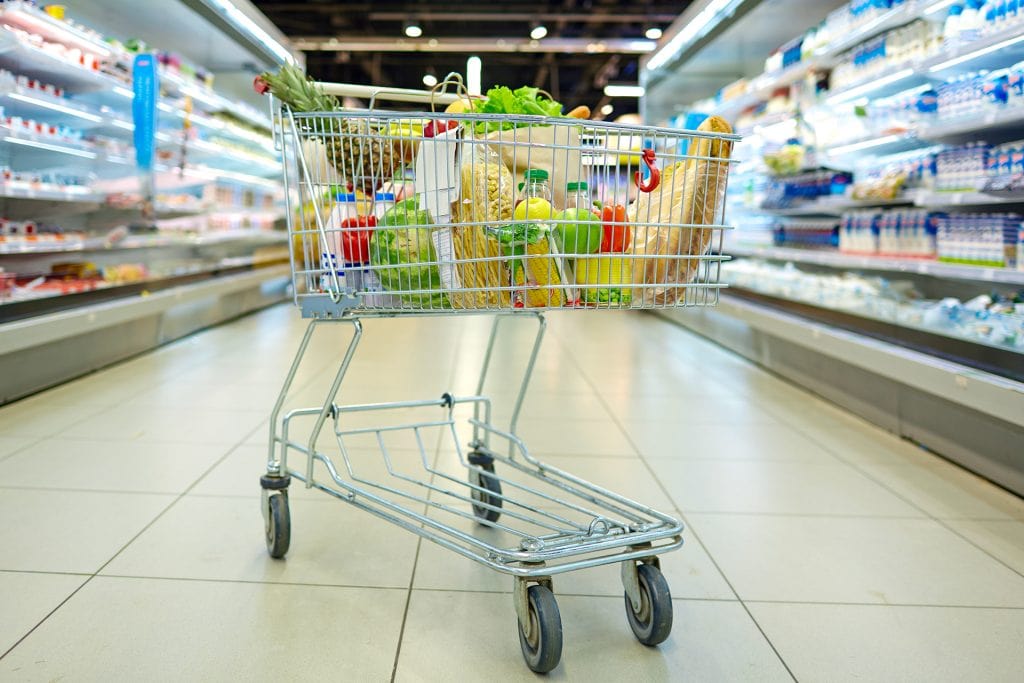 Voller Einkaufswagen mit Lebensmitteln im Supermarktgang